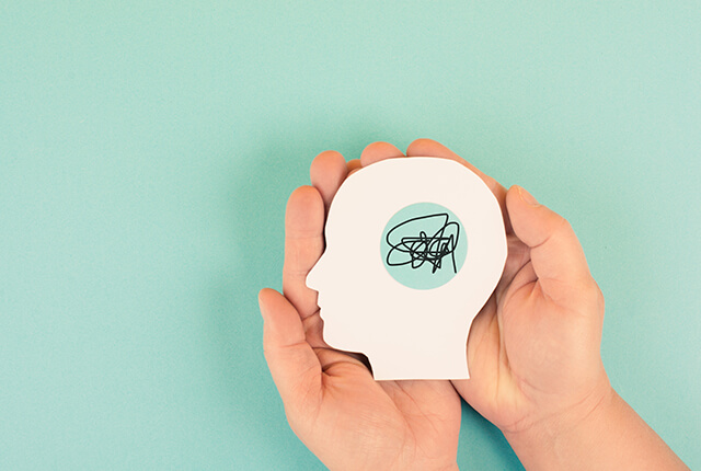 ADHDやストレスを象徴するイメージ。頭の形の紙の中に混乱した線が描かれている。